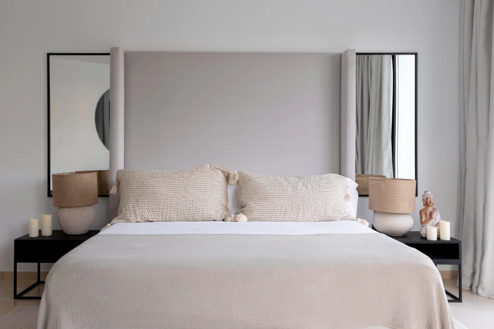 A bedroom featuring a solid upholstered headboard firmly placed against a windowless wall